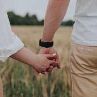 Photo couleur en gros plan d'un couple femme-homme amoureux main dans la main marchant dans un champs - Pexels 9635715